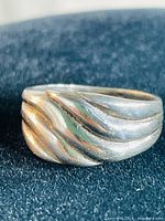 Front angle of sterling silver ornate ring showing flowing wave pattern design on face