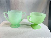 Photo showing the vintage Fenton jadeite glass creamer and sugar cup side by side on a white surface.
