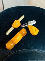 Photo of three vintage white Baltic amber jewelry pieces on black velvet display.