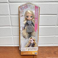 Front view of the Luna Lovegood doll in package showing doll with long blonde hair and grey dress, Harry Potter branding.