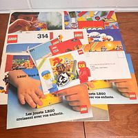 Various vintage Lego instruction booklets and catalogs fanned out on table showing colorful covers and classic Lego logos