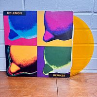 Front cover of the U2 Lemon Remixes album showing pop-art style artwork with bright colors and the yellow translucent vinyl partially visible.