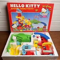 Photo of the vintage Hello Kitty Heliport rollercoaster toy set in original foam insert with box behind, showing components like helicopter, train, tracks, and structures.