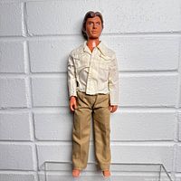Full front view of the vintage Indiana Jones figure dressed in a white jacket and beige pants, barefoot, standing against a white textured wall.