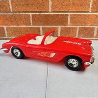 Side view of the red toy Corvette car showing white interior and flame decals on the side with the text 'RIPTIDE' on hood.