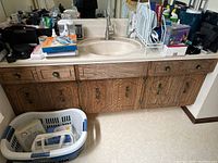 Wide view showing bathroom countertop with many items including personal hygiene products, radios, hair dryer, and cologne.