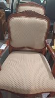 Front view of chair showing carved wood crest rail and upholstered seat