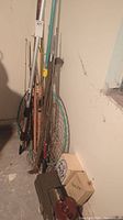 Corner overview showing multiple fishing rods, landing net, wooden box and plastic tackle box