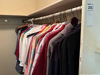 Clothing rack with assorted men's golf and casual shirts in various colors, mostly long-sleeve and polo styles hung on metal hangers.