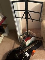 Overview of all items: guitar in gig bag, music stand, box of books and metronome
