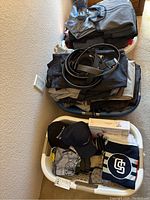 Two laundry baskets showing folded pants and shirts in the top basket and hats, a Calvin Klein box and socks in the bottom basket