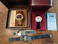 Overview of four watches laid out, showing boxes and lot tag