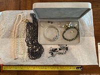 Multiple faux pearl necklaces, bangle, bracelet and earring parts on tray