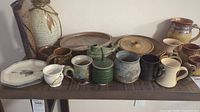 Wide shot showing entire collection of pottery pieces arranged on wooden surface