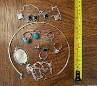 Full assortment of necklaces, rings, brooches, and earrings laid out with measuring tape