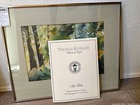 Framed framed watercolor painting by Mimi Jones with Thomas Kinkade collector print certificate displayed in front