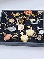 Tray of assorted vintage costume jewellery including earrings, cufflinks, chains, pins, and brooches on black felt
