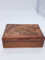 Top view of wooden box showing carved First Nations animal design on lid.