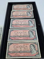 Full view of five 1954 Canadian $2 bills arranged in a black tray showing front side with queen's portrait.