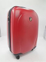 Red hard shell Heys suitcase angled view showing overall shape and wheels.
