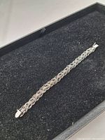 Full length view of the silver woven link bracelet in black display box.