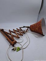 Full view of vintage teakwood extending wall lamp with orange and red fabric shade, electrical cord and plug visible.