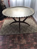 Full view of the vintage Moroccan brass table showing the brass tray top and wood base on a patterned rug.