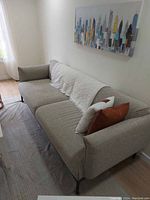 Angled front view of grey sofa on black metal legs with decorative throw and cushions