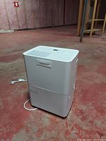 Front and side view of white Noma dehumidifier showing top vents, controls and water reservoir below.