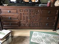 Front view of the vintage wooden buffet showing six drawers, two central doors with geometric carved design, and decorative metal drawer pulls.