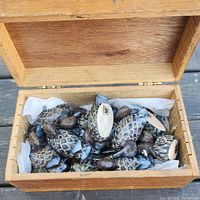 Wooden box open to show approximately 20 hand carved and painted wood duck figurines inside.