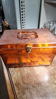 Closed amber plastic sewing box on wooden surface