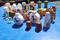 Complete view of the lot showing various vintage and collectible salt and pepper shakers arranged on blue surface, including ceramic, wood, glass, and metal items.