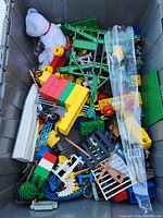 Top view of the bin showing various Lego blocks, toy pieces, white dog figure, and some wheels.