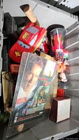 Photo shows several items including Lightning McQueen car, cassette player, dolls, colorful miniatures in a plastic cylinder, and some other collectibles in a bin.