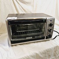 Front view of a large Black & Decker toaster oven showing the glass door, wire rack inside, and three control knobs on the right side.