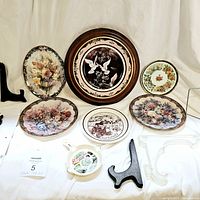 Full view of six collector plates arranged with five plate holders, two wooden and three plastic.