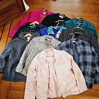 Photo of all 10 vintage blazers and jackets arranged on a wooden floor, showing variety of colors and patterns