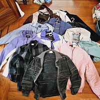 Photo showing all 11 vintage and newer coats and jackets in various colors and fabrics laid out on wooden floor