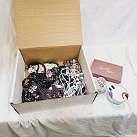 Box filled with assorted vintage costume jewelry pieces including various beaded necklaces and small accessory boxes.