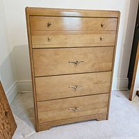 Front view of vintage blonde auburn wooden tall dresser showing all drawers and metal handles