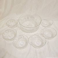 Overview of the entire set showing one larger bowl and six smaller bowls arranged on a light fabric background.