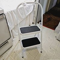 Vintage solid folding step stool with two steps placed in a kitchen corner, shown from front angle.