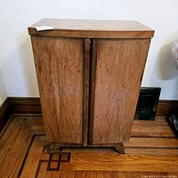 Front view of vintage wood Mid Century Modern bottle bar cabinet showing two doors and carved central handle groove