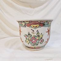 Front view of vintage hand painted flower pot planter showing floral and bird designs on white ceramic.