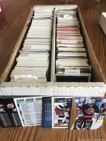 Top view of a long divided cardboard box filled with hockey cards tightly packed, left side full of checklists, right side random cards with labels.