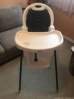 Front view of white Cosco highchair showing tray, fabric backrest and black legs