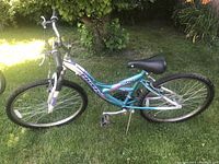 Side view of the teal and white Huffy Rival bike showing the full profile with 21-speed gear system, inflated tires, and standard mountain bike features.