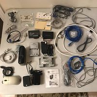 Full lot overview showing multiple cables, chargers, adapters, battery chargers, wired mouse, and two white wall network plates