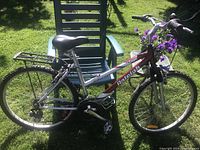 Full side view of the Raleigh Portage bike leaning on a green chair, showing frame, tires, seat, and rear rack.